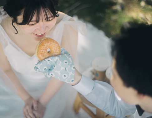 ピクニック中にドーナツを食べる自然体のおふたりのロケーション撮影