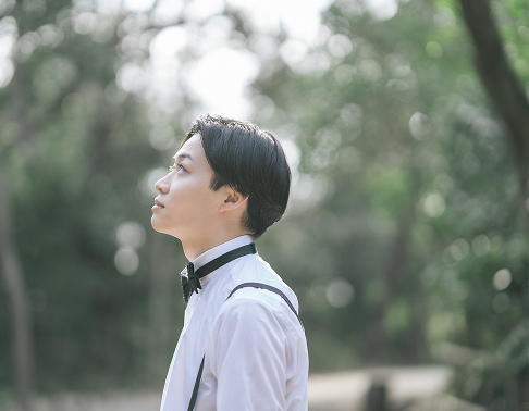 緑の中で自然体にたたずむ新郎のソロ写真