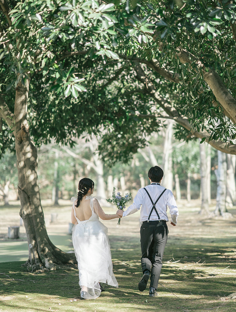 芝生の上を走る新郎新婦の自然体なウェディングフォト