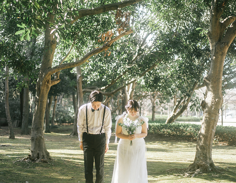 21世紀の森と広場でお辞儀する新郎新婦のウェディングフォト