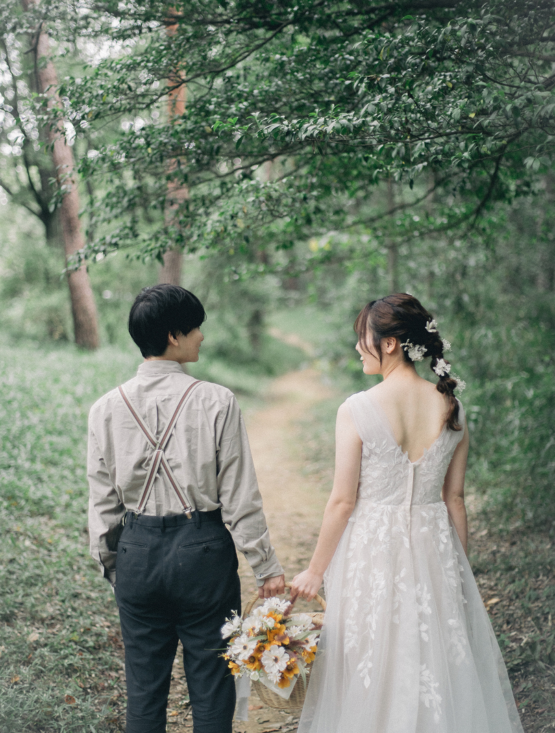 ブーケを持って森を歩く新郎新婦