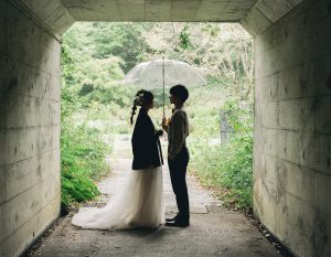 トンネルで傘を差す新郎新婦