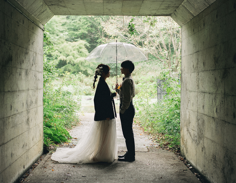 トンネルで傘を差す新郎新婦