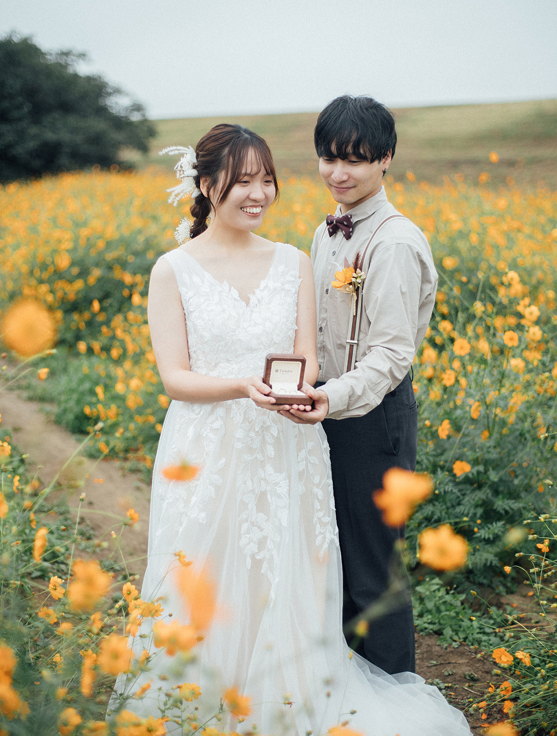 コスモス畑で指輪の箱を持つ新郎新婦