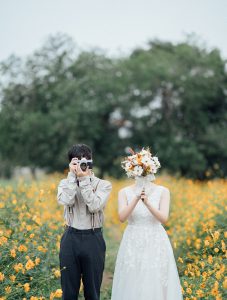 カメラとブーケで顔を隠す新郎新婦