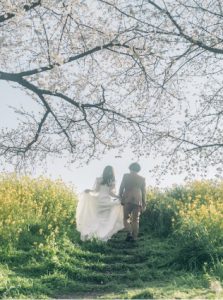 桜の下を歩く新郎新婦の後ろ姿