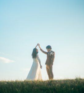 青空の下で手を取り合う新郎新婦