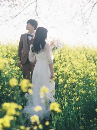 菜の花畑で寄り添う新郎新婦