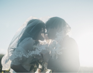 ベールの中で額を寄せる新郎新婦