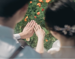花畑を背景に手を重ねる新郎新婦