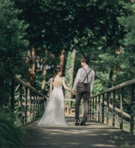 森の橋を歩く新郎新婦の後ろ姿