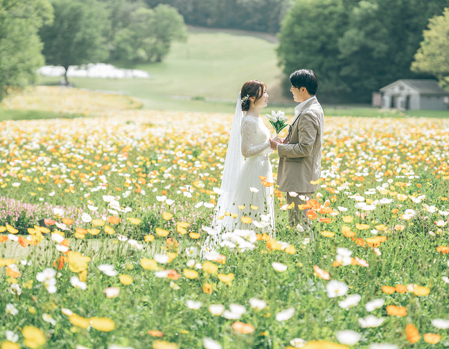 春の花畑で向かい合う新郎新婦