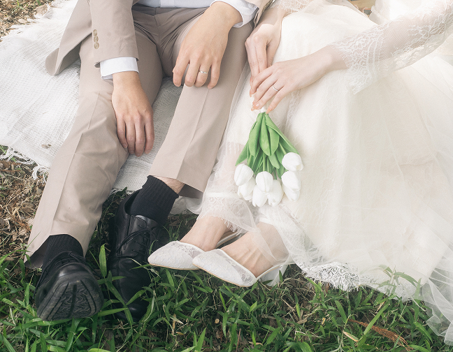 芝生に腰掛ける新郎新婦とチューリップ
