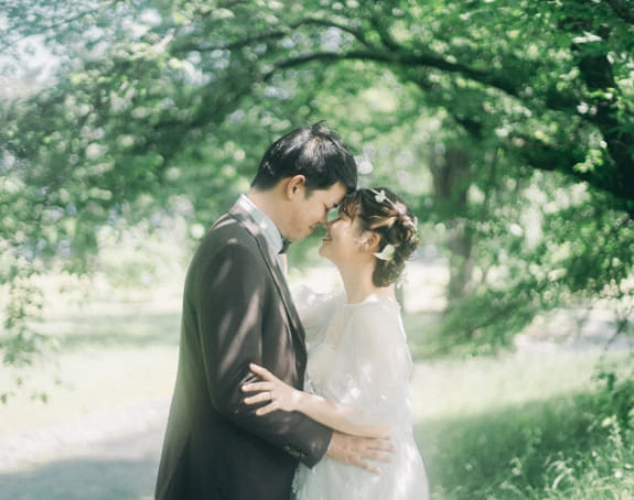 緑の中で額を寄せ合う新郎新婦