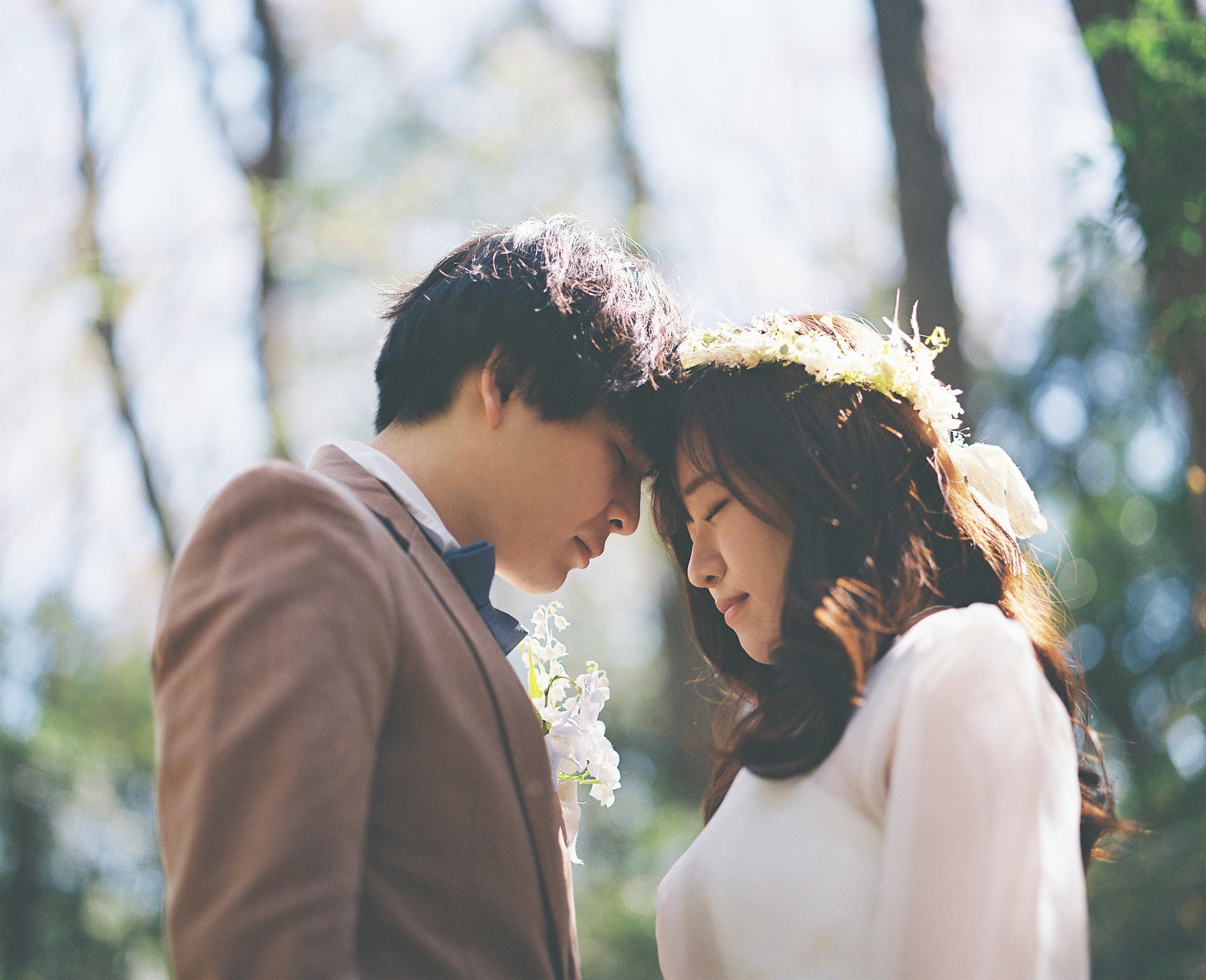 森で額を寄せ合う新郎新婦