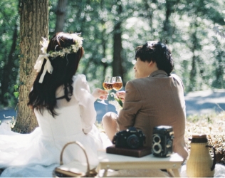 森のピクニックで乾杯する新郎新婦
