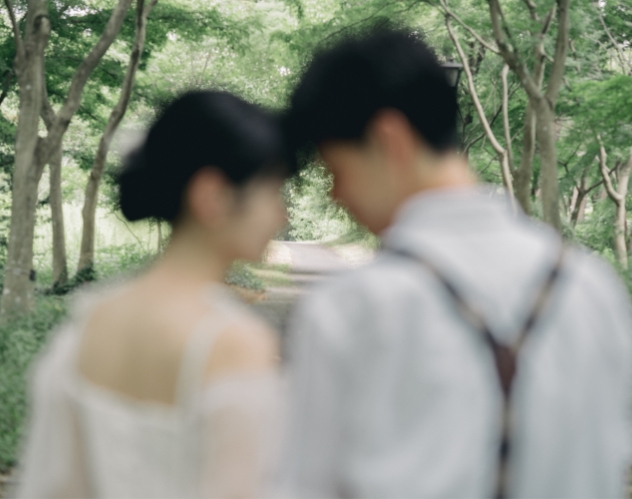 森の小径で額を寄せ合う新郎新婦