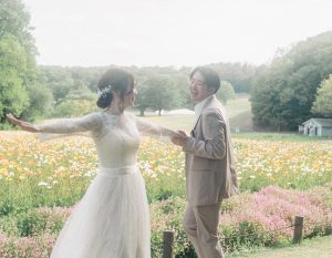 花畑で手を取り合う新郎新婦