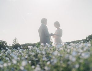 ネモフィラ畑で向かい合う新郎新婦のシルエット