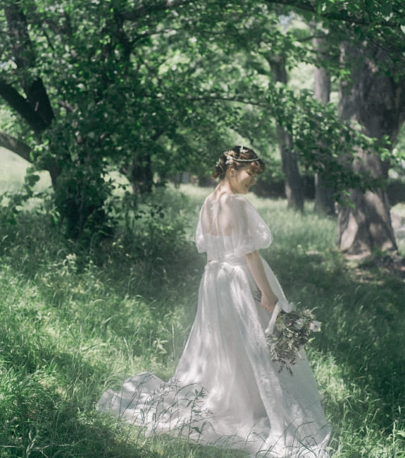 木立を歩くウェディングドレスの花嫁
