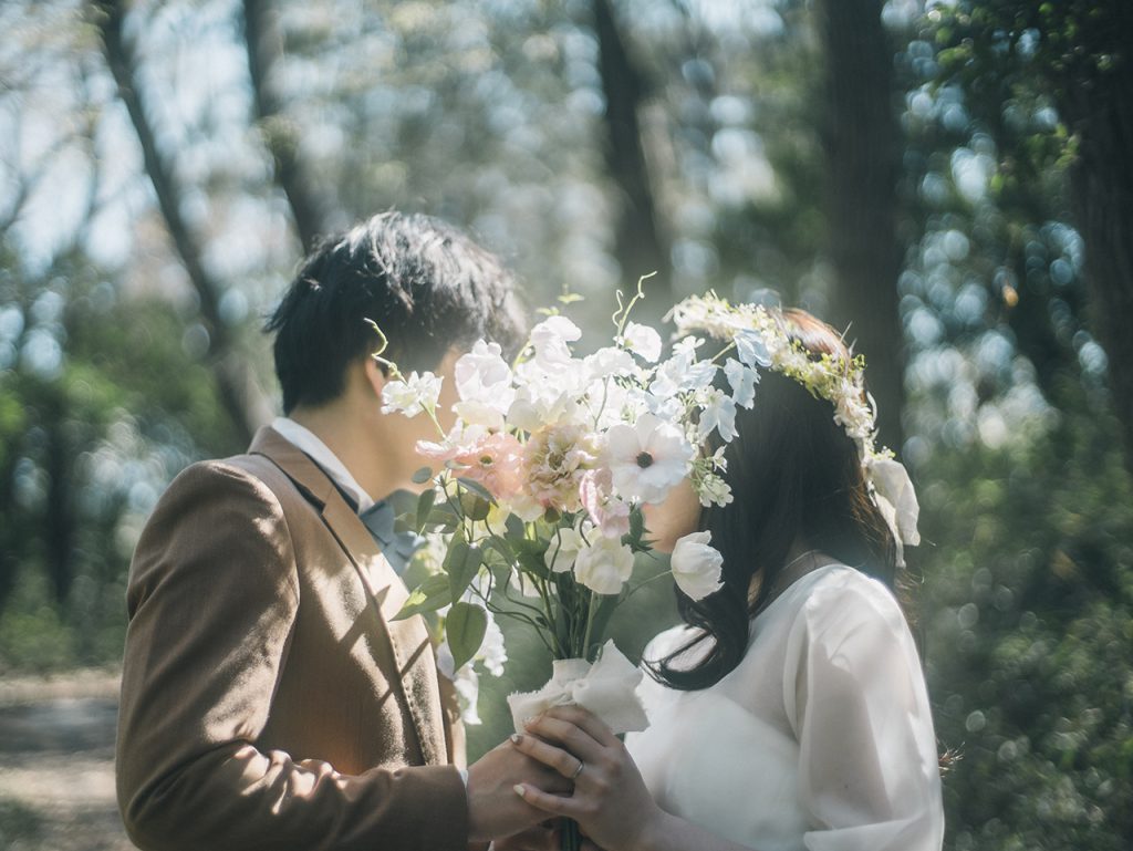 森の中でブーケ越しに向かい合う新郎新婦