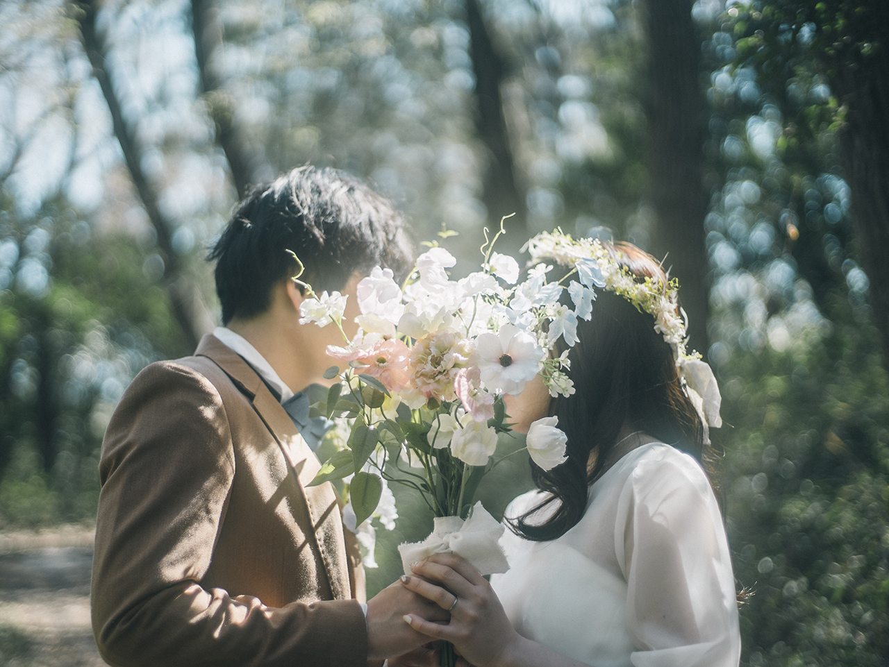 森の中でブーケ越しに向かい合う新郎新婦