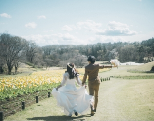 花畑へ駆け出す新郎新婦の後ろ姿