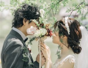 花越しに見つめ合うウェディング姿の二人