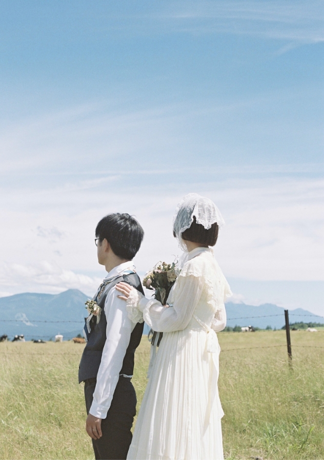 高原で背中合わせに立つ新郎新婦