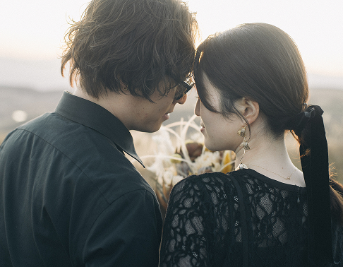 黒い衣装で額を寄せ合う新郎新婦