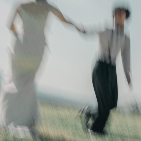 草原を駆けるウェディング姿の二人