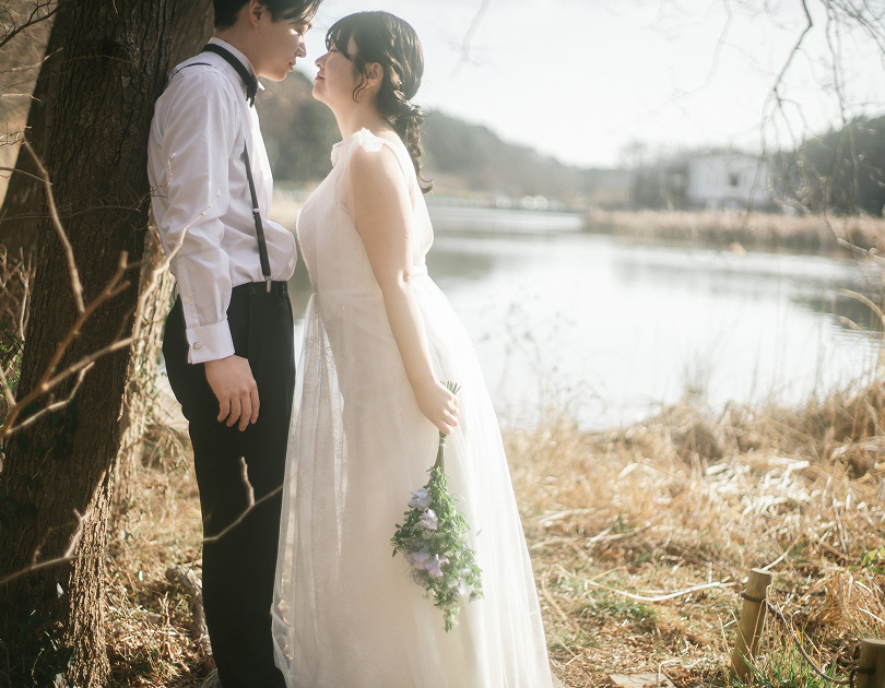 池のほとりで額を寄せる新郎新婦