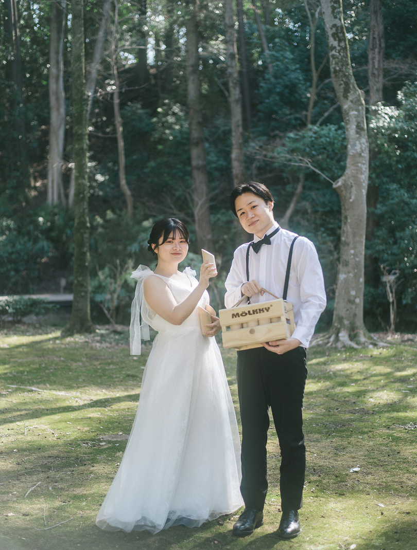 撮影小物を持って並ぶ新郎新婦