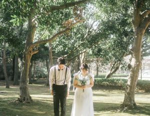 大樹の下でお辞儀をする新郎新婦