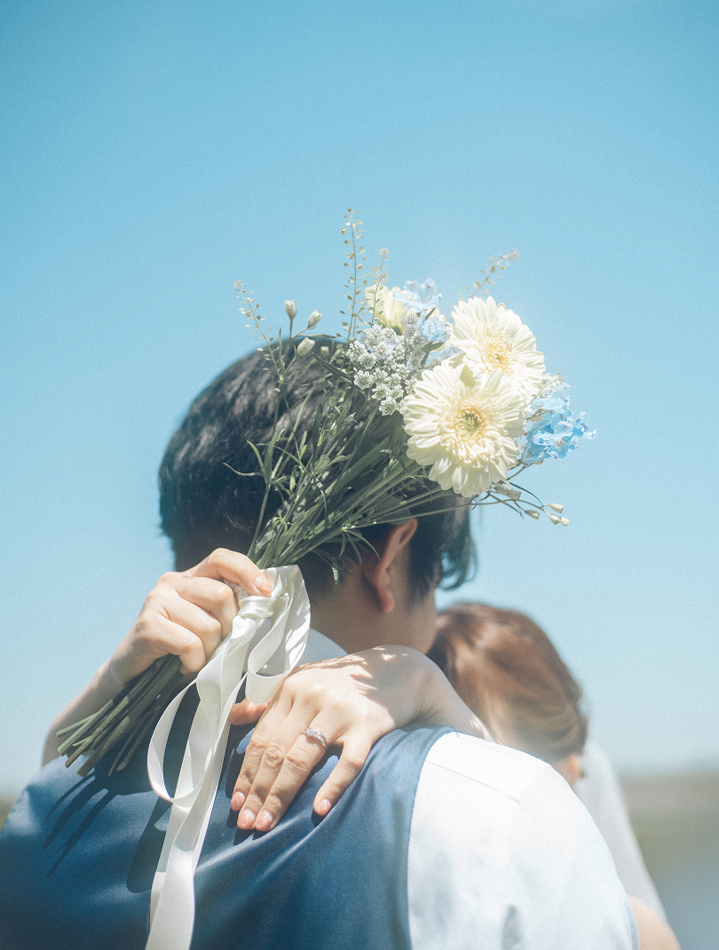 新郎の肩越しにブーケを掲げる花嫁