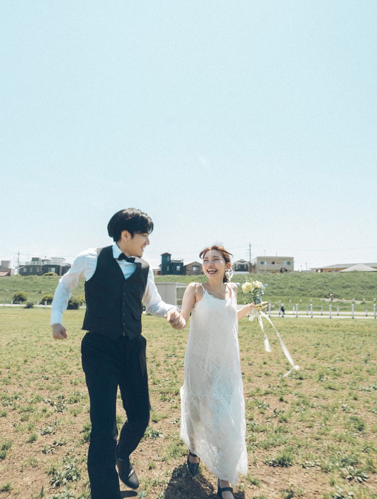 河川敷を手をつないで走る新郎新婦