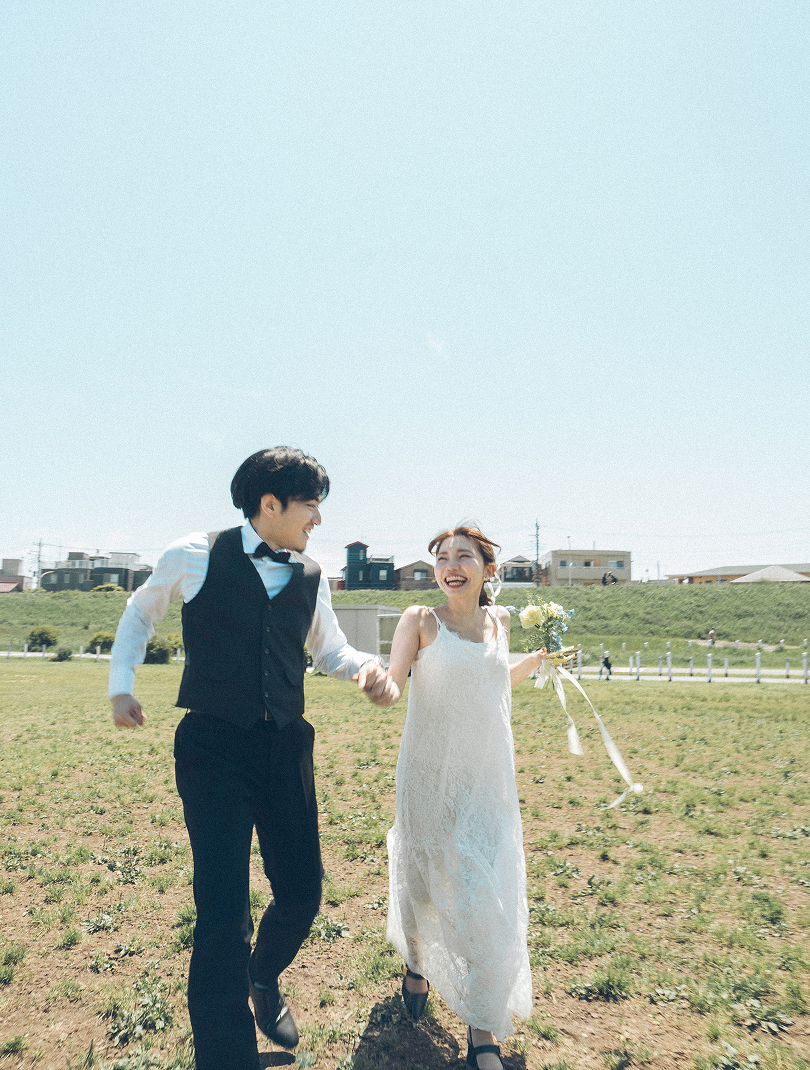 河川敷を手をつないで走る新郎新婦
