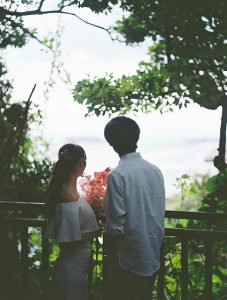 海を望む木陰に立つ新郎新婦