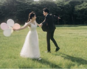芝生で風船を持ち踊る新郎新婦