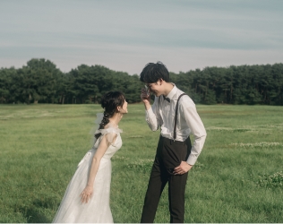 芝生で向かい合って笑う新郎新婦