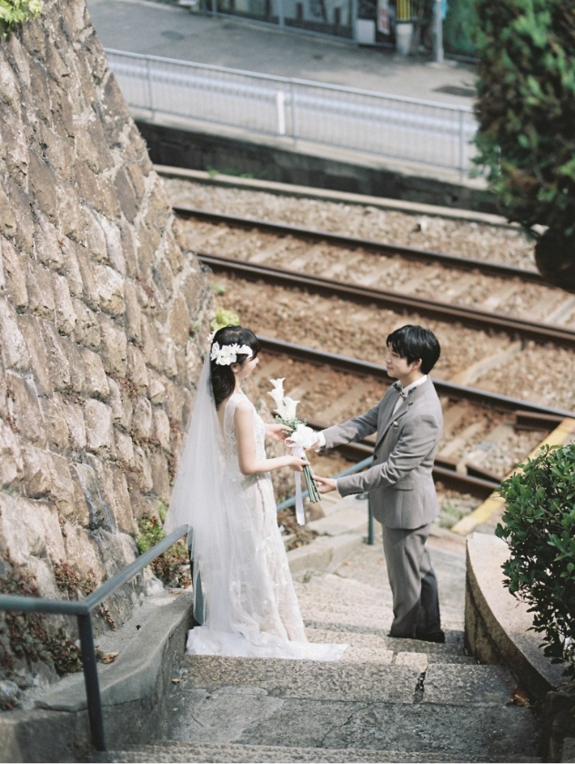 線路沿いの階段で手を取り合う新郎新婦
