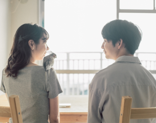 室内で肩を並べる二人とオカメインコ