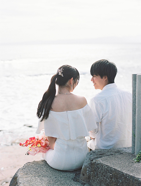 海辺の護岸に座る新郎新婦