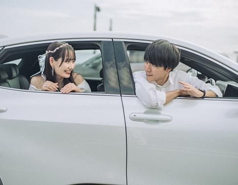 車の窓から顔を出す新郎新婦