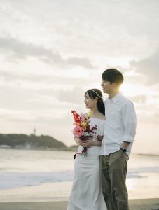 夕暮れの海辺に立つ新郎新婦