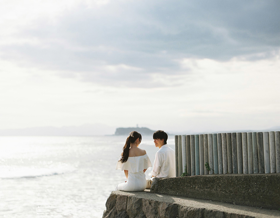 七里ヶ浜の護岸に座る新郎新婦の遠景
