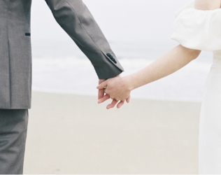 海辺で手をつなぐ新郎新婦の手元