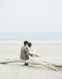 流木に腰掛ける新郎新婦