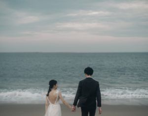阿字ヶ浦海岸で手をつなぐ新郎新婦
