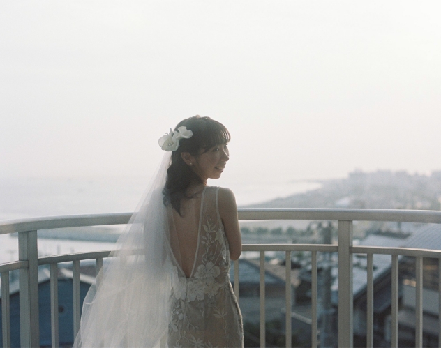 高台から海を眺める花嫁の後ろ姿